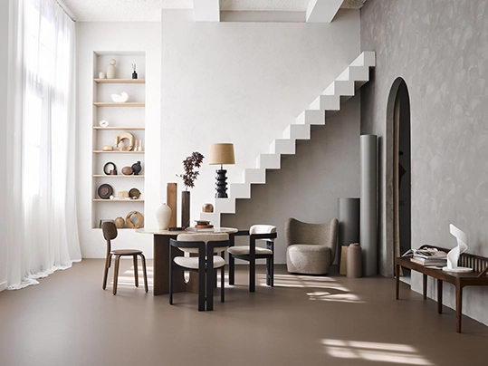 Stylish interior with smooth taupe flooring, a floating white staircase, and a modern round dining setup.