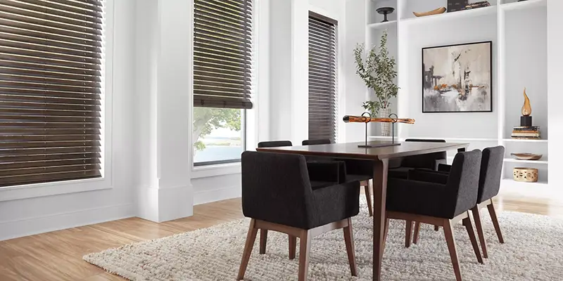 Dining room with dark wood venetian window blinds, a modern dining set, and a textured area rug.