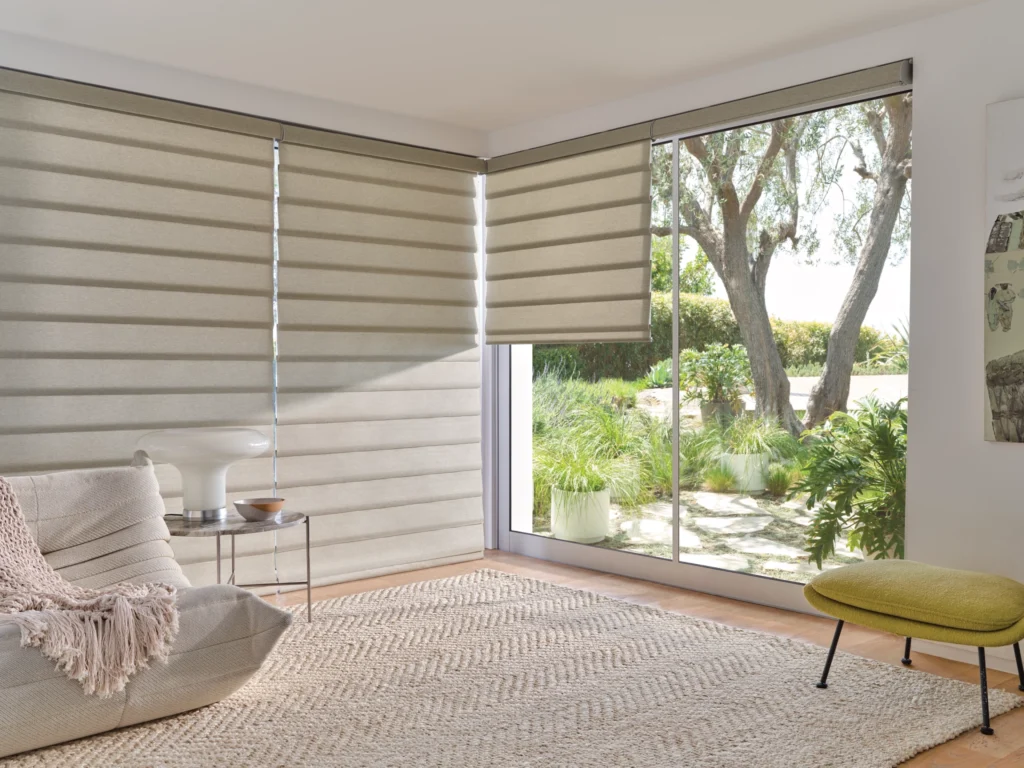 Sunlit room featuring light beige horizontal window shades, a woven rug, and garden views.